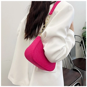 Magenta felt hobo bag with gold chain strap worn over a white oversized blazer