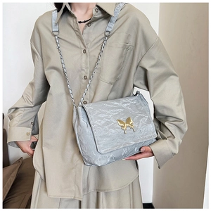 Close-up of light grey shoulder bag with pleated texture and golden butterfly clasp