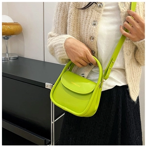 Neon green mini crossbody bag shown with beige cardigan and black lace skirt