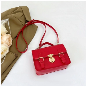 Detail of red PU leather crossbody bag featuring gold hardware and a circular swivel lock
