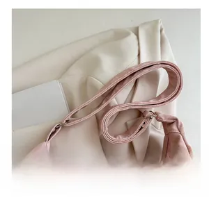 Detail of light pink textured fabric handbag with elegant pleated design and silver buckle