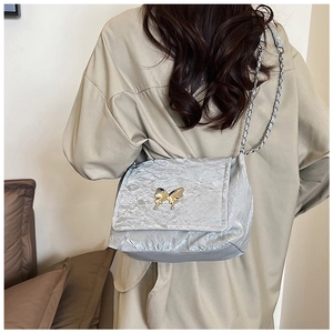 Close-up of a metallic pleated shoulder bag featuring a gold butterfly buckle and chain strap