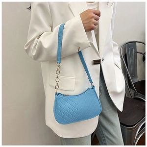 Detail of light blue quilted felt bag with V-shaped stitching and gold chain strap