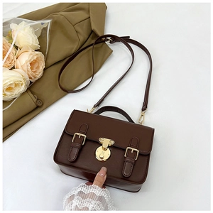 Detail of vintage dark brown faux leather satchel with golden hardware and top handle