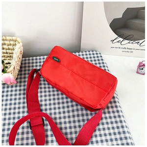 Close-up of red nylon pillow bag with adjustable strap and green EAIMT brand label