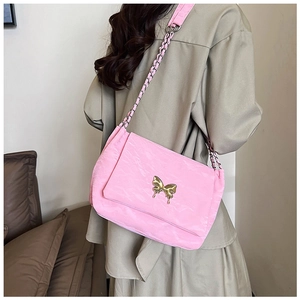 Detail of pink pleated shoulder bag with golden butterfly charm and chain strap