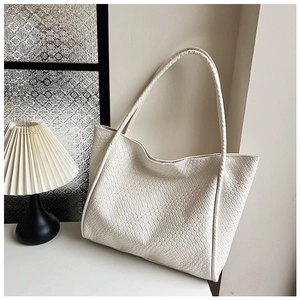 Detailed close-up of woven cream tote bag with Intrecciato leather texture and slim straps