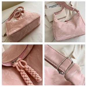 Detail view of pink shoulder bag with pleated texture and braided rope zipper pulls