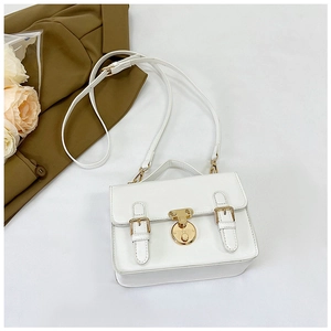 Detail of white PU messenger bag showing the round gold lock and decorative strap buckles