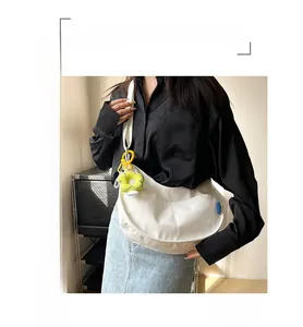 Sac hobo en toile blanche avec breloque tournesol porté par un mannequin