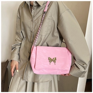 Detail of pink pleated crossbody bag featuring a golden butterfly buckle and chain strap