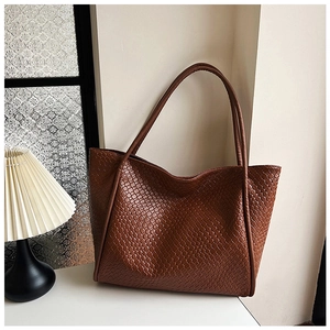 Close-up of caramel brown woven tote bag featuring high-quality leather texture and strap