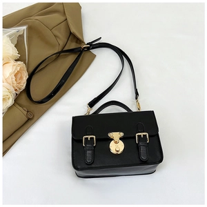 Close-up of black retro messenger bag with golden metal buckle and top handle details