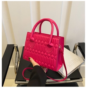 Detail of fuchsia wave quilted leather handbag with gold hardware and dual handles