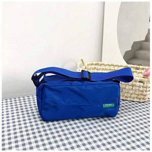 Detail of navy nylon shoulder bag with adjustable strap and brand label on a checkered cloth