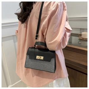 Detail view of stylish color-block handbag with silver glitter finish and gold twist lock
