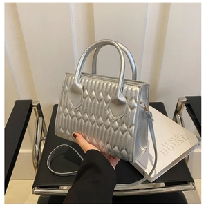 Detail of silver metallic quilted handbag with diamond pleats and slender strap