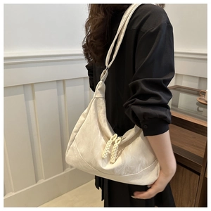 Detailed view of white half-moon underarm bag with textured fabric and woven zipper pull