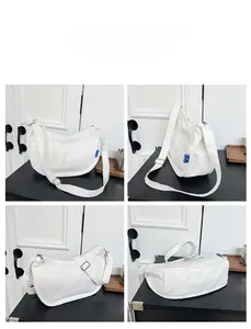 Vue détaillée du sac croissant en toile blanche avec bandoulière et étiquette bleue