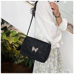 Detail of black pleated shoulder bag with silver butterfly buckle and chain strap