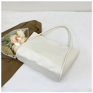 Detail of white woven texture on a minimalist tote bag with floral prop and brown blazer