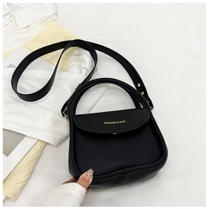 Vue à plat d'un sac à main trapèze en cuir noir mat avec logo doré sur fond de vêtements