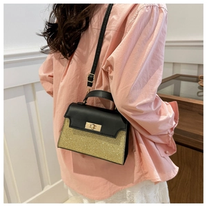 Detailed view of bicolor crossbody bag featuring black leather and golden glitter finish