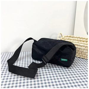 Detail of black nylon crossbody bag featuring thick shoulder strap and green brand label