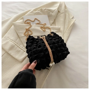 Detailed view of black bubble textured bucket bag with gold chain and pearl accents