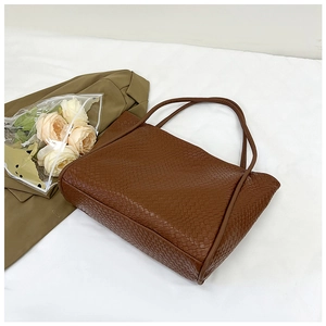 Close-up of the woven texture and double handles on this brown retro tote bag
