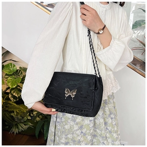 Detailed view of the black pleated bag with a silver butterfly ornament and chain strap