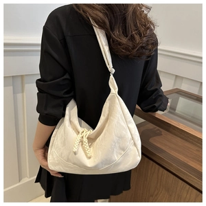 Detail of cream shoulder bag featuring pleated texture and woven rope design
