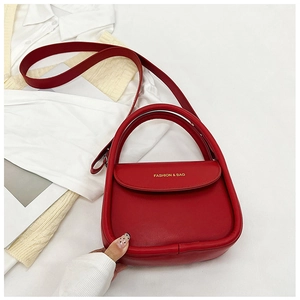 Détail d'un sac à main rouge tendance avec lettrage doré sur le rabat et poignée
