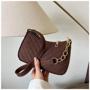 Detailed view of dark brown quilted felt shoulder bag with golden chain and zip closure