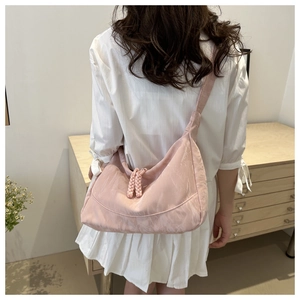 Detailed view of pink crescent bag with woven rope knot on textured fabric