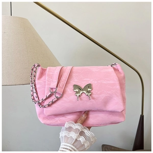 Detailed shot of pink pleated shoulder bag with silver butterfly charm and chain strap