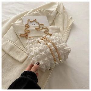Detail of white pleated bucket bag with gold chain strap and pearl drawstring charms