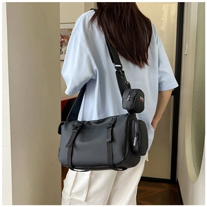 Detail of black waterproof crossbody bag featuring a detachable mini round pouch on strap