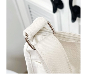 Détail de la boucle en métal argenté et coutures nettes sur le sac fourre-tout en toile