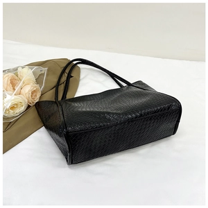 Detail of black woven tote bag showing premium PU leather texture and woven pattern