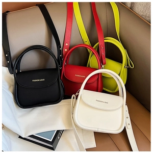 Mini sacs à bandoulière en quatre couleurs posés sur un canapé en cuir avec anses