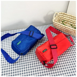 Detail of nylon crossbody pillow bag in vibrant blue and red colors with green logo label