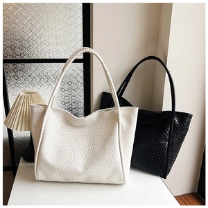 Detail of woven texture on large tote bags in cream and black colors