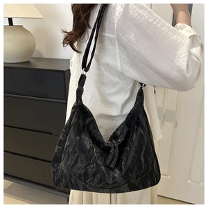 Detail of black pleated Hobo bag featuring woven zipper pull on a white shirt model