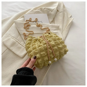 Detail of bubble texture crossbody bag with gold chain strap and pearl drawstring accents