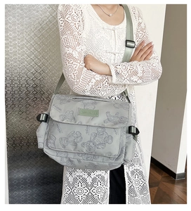 Detail of printed grey nylon tote bag with bear pattern and green logo label