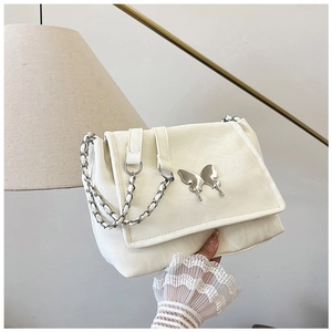 Detail of silver butterfly buckle and woven chain strap on cream shoulder bag