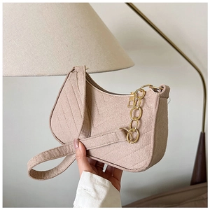 Close-up of quilted felt baguette bag with gold chain and V-shaped stitching detail
