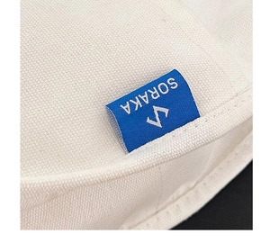 Détail macro du tissu en toile blanche avec une étiquette de marque SORAKA tissée bleue