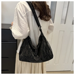 Detail of black textured crescent bag showing glossy wrinkled fabric and knot drawstring